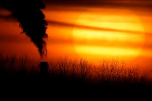 FILE - In this Feb. 1, 2021 file photo, emissions from a coal-fired power plant are silhouetted against the setting sun in Independence, Mo. President Joe Biden faces a vexing task as he convenes a virtual climate summit on Thursday. He is expected to present a nonbinding but symbolic goal to reduce greenhouse gas emissions that will have a tangible impact not only on climate change efforts in the U.S. but throughout the world. (AP Photo/Charlie Riedel, File)