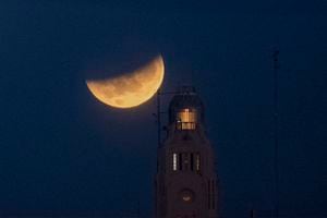 The moon sets behind the Montevideo port, in Uruguay, Wednesday, May 26, 2021, during a lunar eclipse, also known as a super blood moon. (AP Photo/Matilde Campodonico)