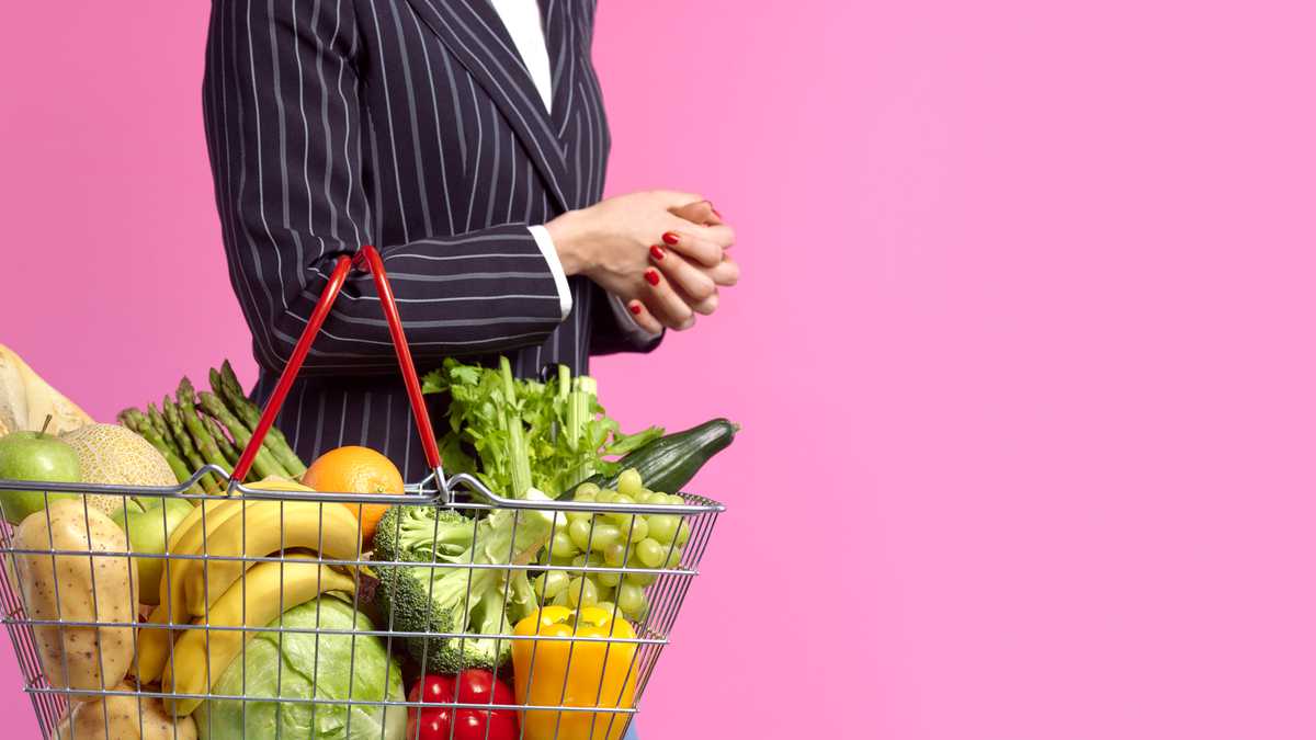 Mujer sosteniendo una cesta llena de frutas y verduras. Reforma Tributaria.