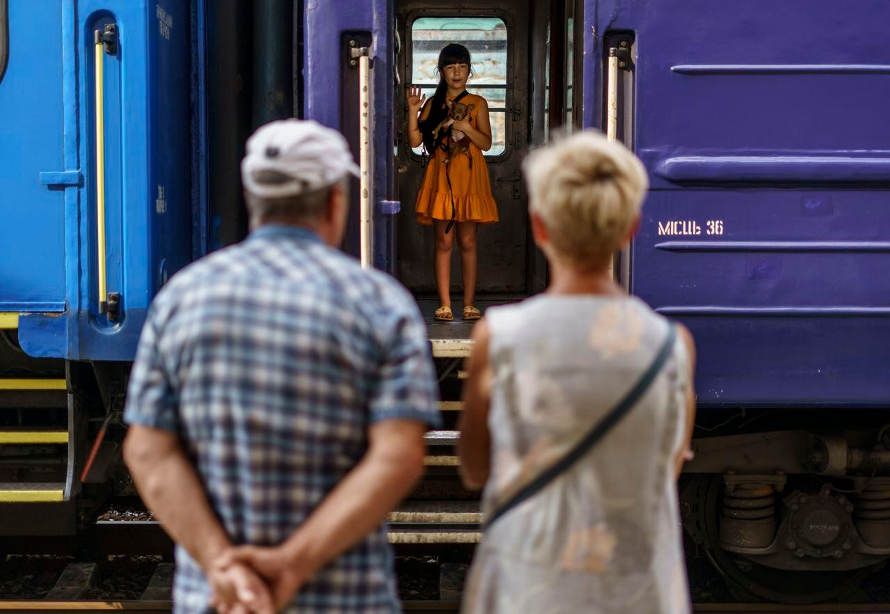 A young girl holds her dog while waving goodbye to her grandparents from an evacuation train departing Pokrovsk, Donetsk region, eastern Ukraine, Tuesday, Aug. 2, 2022, for a safer part of the country to the west. The government issued an order to residents to leave the Donetsk region in the face of the Russian offensive as they are preparing for fall and winter and fear that many there may not have access to heating, electricity, or even clean water. (AP Photo/David Goldman)