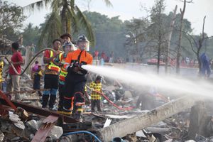 Un bombero rocía agua tras una explosión en un almacén pirotécnico en la provincia de Narathiwat, Tailandia, el sábado 29 de julio de 2023. (AP Foto/Kriya Tehtani)