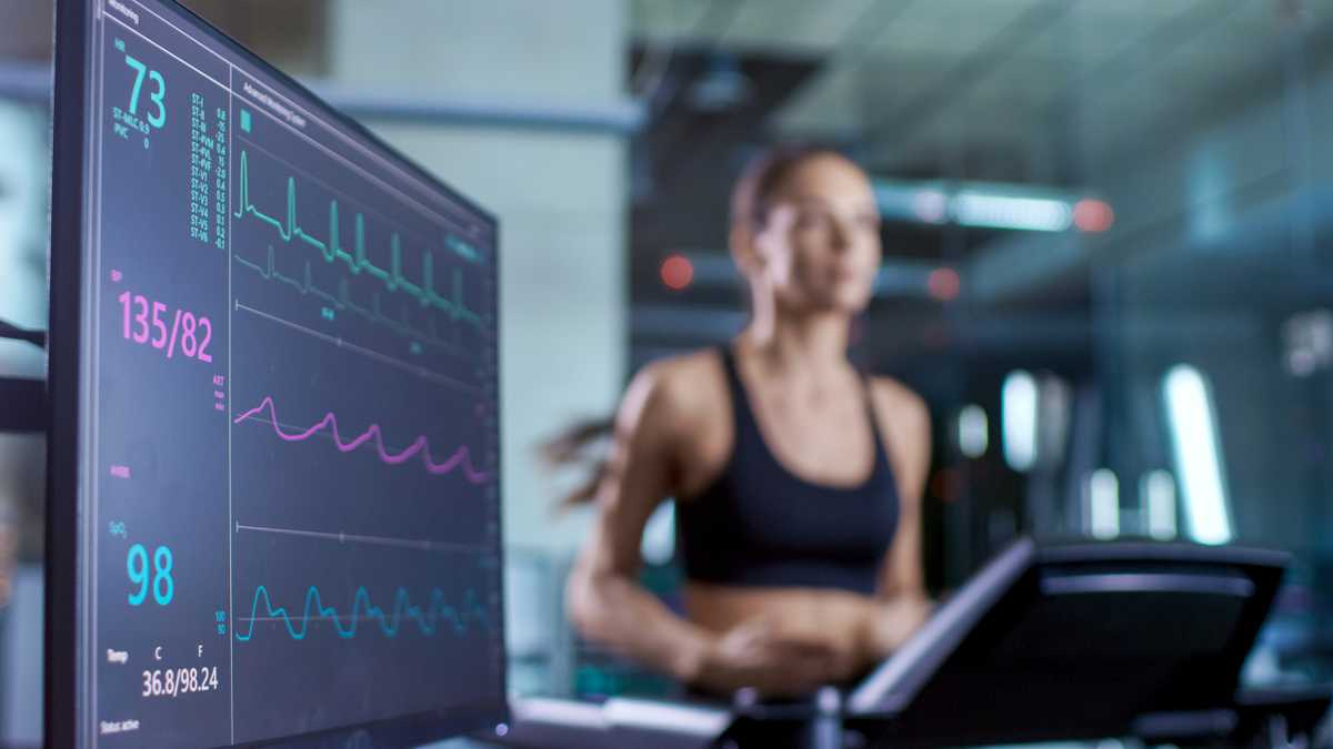 Medical Monitor Shows EKG Reading of a Woman Athlete Running on a Treadmill. Focus on Monitor.