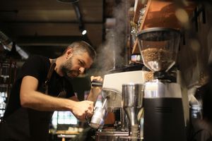 Barista Making Coffee For Customers At Cafe