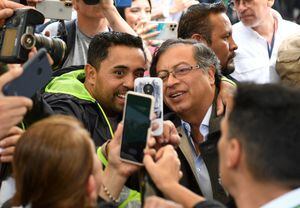 Colombian left-wing presidential candidate Gustavo Petro (R) poses for a picture with a suppporter as he arrives at a polling station during the presidential runoff election in Bogota, on June 19, 2022. - Colombians vote for a new president in an election filled with uncertainty, as former guerrilla Gustavo Petro and millionaire businessman Rodolfo Hernandez vie for power in a country saddled with widespread poverty, violence and other woes. (Photo by Daniel MUNOZ / AFP)