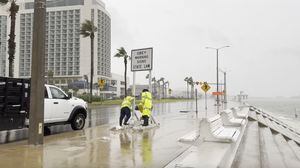In this frame grab from video, workers secure a sign as strong winds blow in from Tropical Storm Harold, in Corpus Christi, Texas, Tuesday, Aug. 22, 2023. (Stringr via AP)