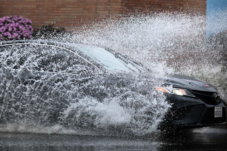 Un automóvil conduce bajo la lluvia a través de aguas pluviales durante una tormenta de invierno en Los Ángeles, California, el 14 de marzo de 2023. (Foto de Patrick T. Fallon / AFP)