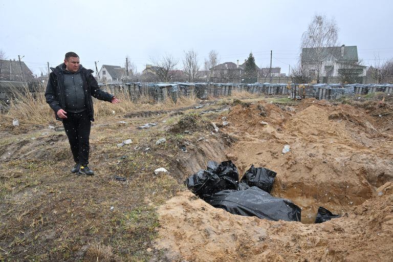 Un hombre señala una fosa común en la ciudad de Bucha, al noroeste de la capital ucraniana, Kiev, el 3 de abril de 2022. - Ucrania y las naciones occidentales acusaron a las tropas rusas de crímenes de guerra después del descubrimiento de fosas comunes y civiles "ejecutados" cerca de Kiev