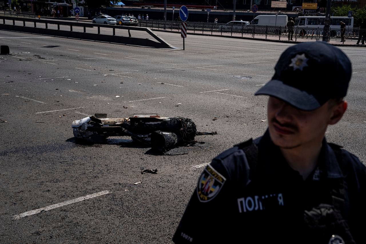 Un oficial de policía ucraniano protege un fragmento del cohete después de un ataque con cohetes rusos en Kiev, Ucrania, el lunes 29 de mayo de 2023.