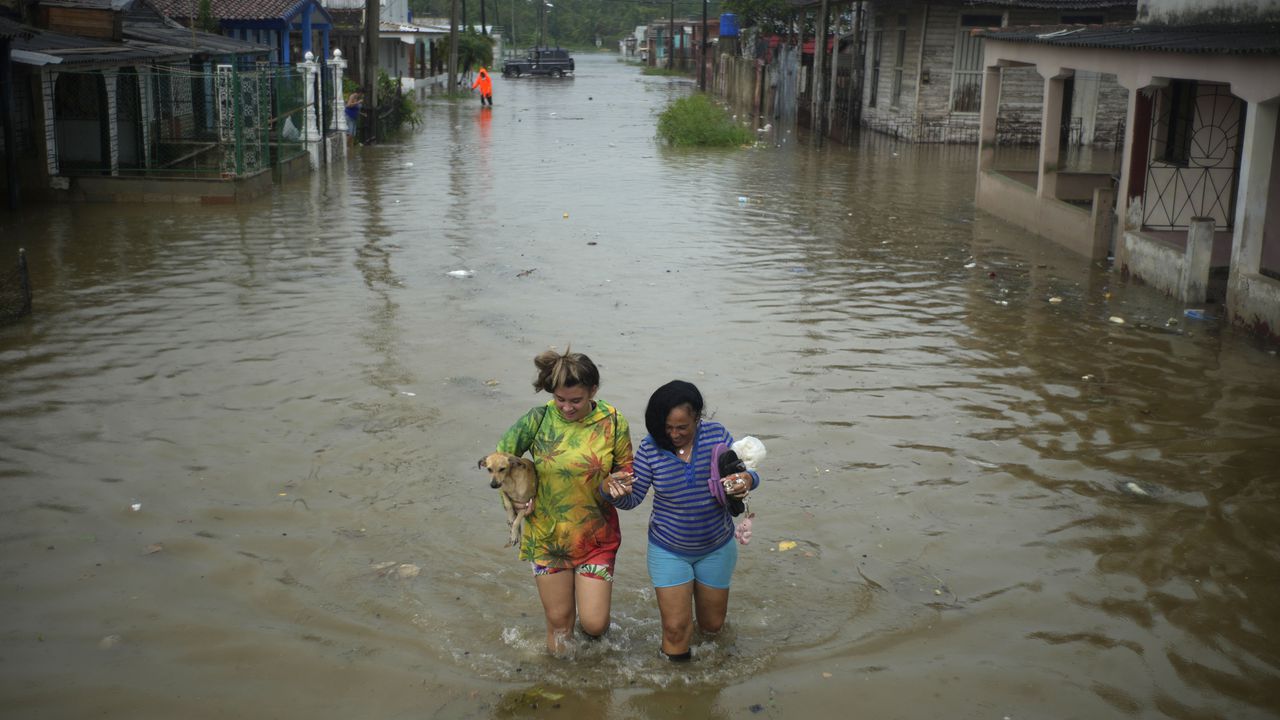 Los residentes caminan por una calle inundada por las lluvias provocadas por el huracán Idalia, en Batabano, Cuba, el martes 29 de agosto de 2023. Idalia se fortaleció hasta convertirse en huracán el martes y se dirigió hacia la costa del Golfo de Florida.