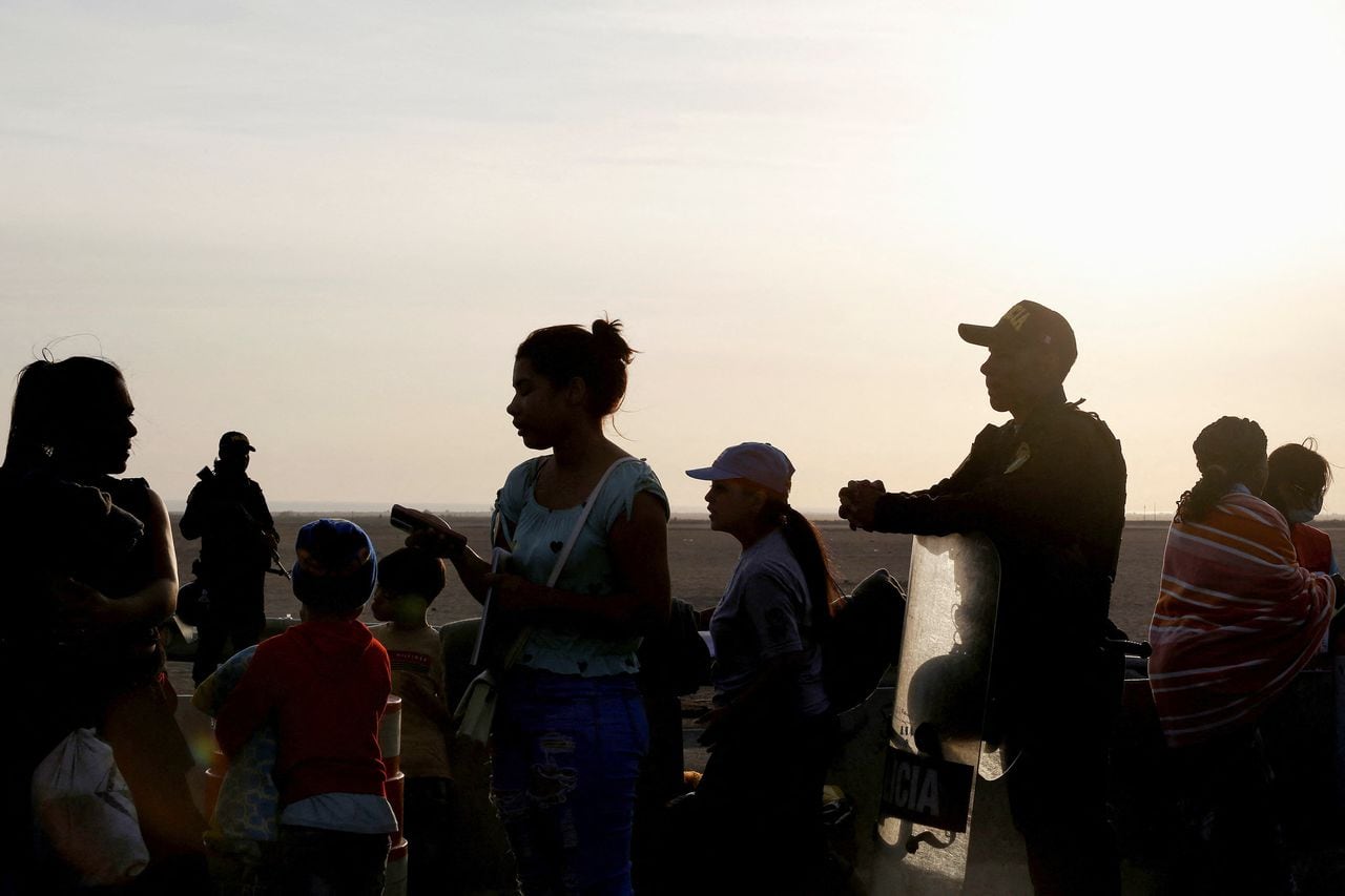 Migrantes indocumentados, en su mayoría de Venezuela, Colombia y Haití, junto a policías peruanos mientras esperan instrucciones de las autoridades locales en la frontera chilena y peruana mientras permanecen atrapados en Chile