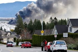 La gente observa cómo arde un incendio en un lote de almacenamiento de vehículos recreativos, días después de que las tormentas azotaran la provincia occidental canadiense de Columbia Británica, provocando deslizamientos de tierra e inundaciones y cerrando carreteras, en Abbotsford, Columbia Británica, Canadá, el 17 de noviembre de 2021. Foto REUTERS / Jennifer Gauthier 