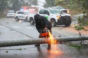 Un trabajador corta un poste de electricidad que fue derribado por el huracán Fiona mientras bloqueaba una carretera en Cayey, Puerto Rico, el domingo 18 de septiembre de 2022. (AP Photo/Stephanie Rojas)