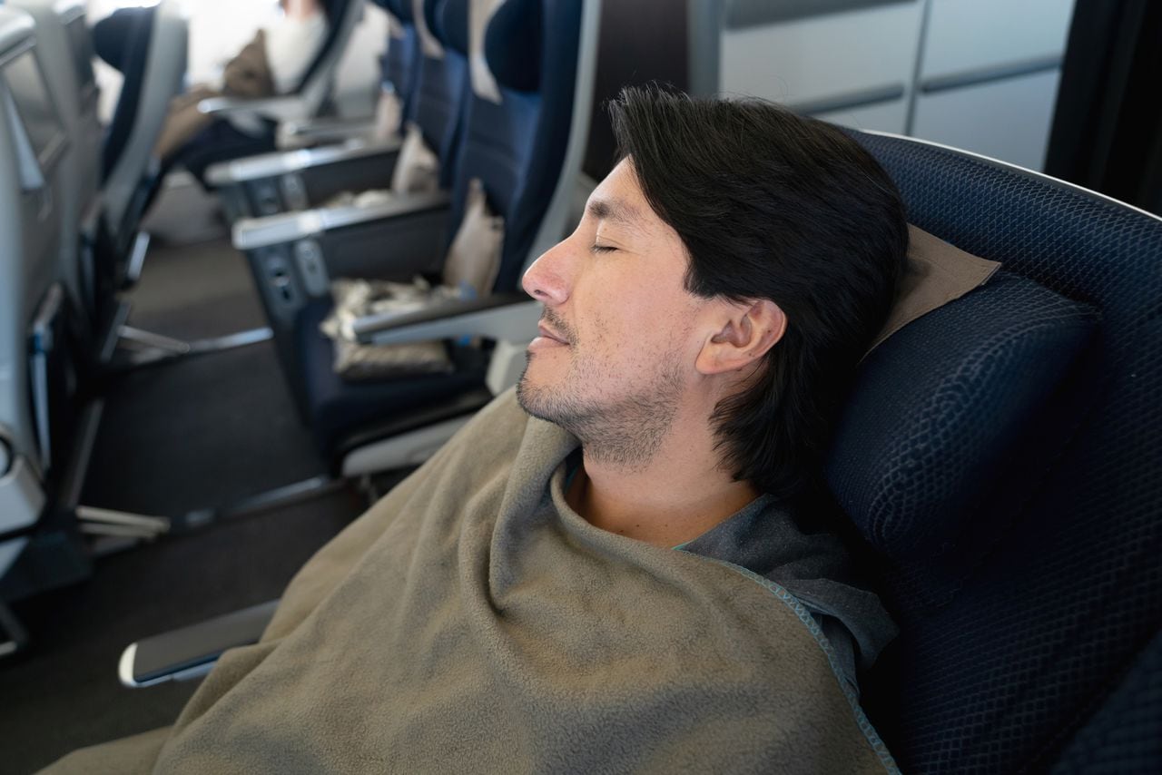Retrato de un hombre que viaja en avión y duerme durante el vuelo - conceptos de viaje