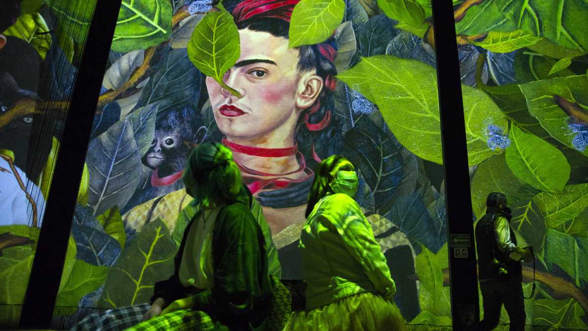 People attend the inauguration of the exhibition "Frida, the immersive experience" in Mexico City on July 6, 2021. - Images of the most famous paintings of iconic Mexican artist Frida Kahlo (1907-1954) are projected on enormous screens and curtains as traditional music plays, as part of a digital exposition that celebrates her life and work, which was premiered on the 114th anniversary of her birth. (Photo by CLAUDIO CRUZ / AFP) / RESTRICTED TO EDITORIAL USE - MANDATORY MENTION OF THE ARTIST UPON PUBLICATION - TO ILLUSTRATE THE EVENT AS SPECIFIED IN THE CAPTION