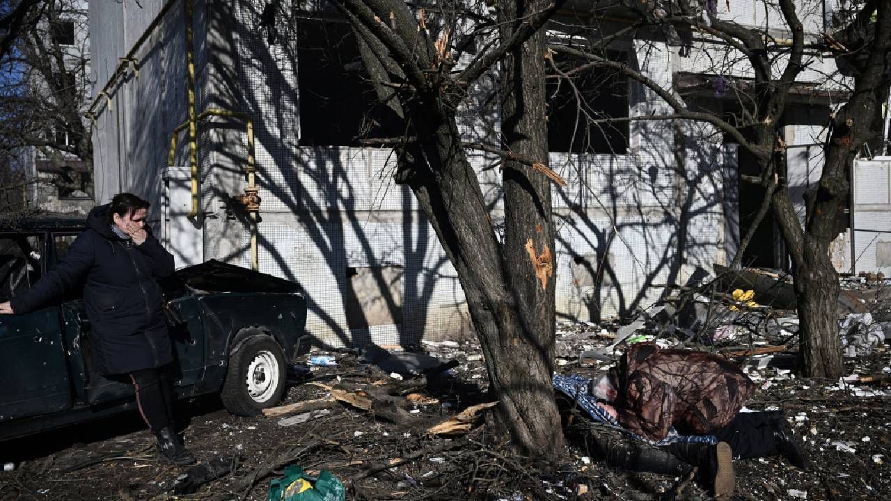La gente reacciona junto al cuerpo de un pariente fuera de un edificio destruido después de los bombardeos en la ciudad de Chuguiv, en el este de Ucrania, el 24 de febrero de 2022.