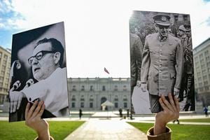 A youth holds a picture of late Chilean President (1970�1973) Salvador Allende (L) and Chilean dictator Augusto Pinochet outside La Moneda Presidential Palace in Santiago, on August 1, 2023. Chile marks the 50th anniversary of general Augusto Pinochet's 1973 military coup on September 11, 2023. (Photo by Martin BERNETTI / AFP)