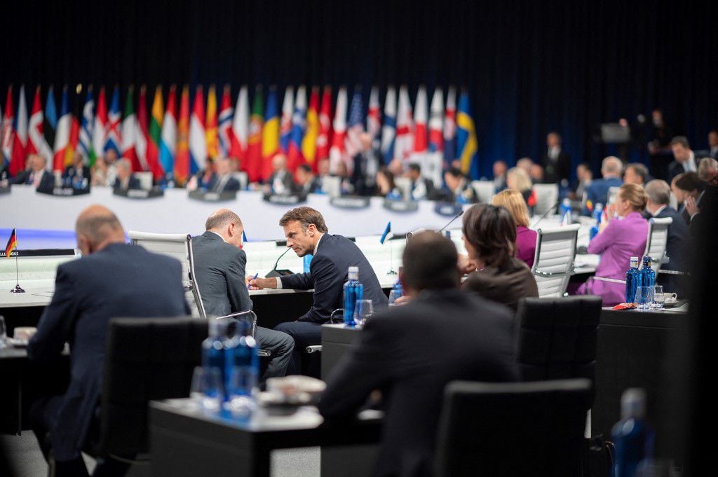 El presidente francés, Emmanuel Macron, habla con el canciller de Alemania, Olaf Scholz, al comienzo de la segunda sesión plenaria de la cumbre de la OTAN en el centro de congresos de Ifema en Madrid, el 29 de junio de 2022. (Foto de Eliot BLONDET / POOL / AFP)