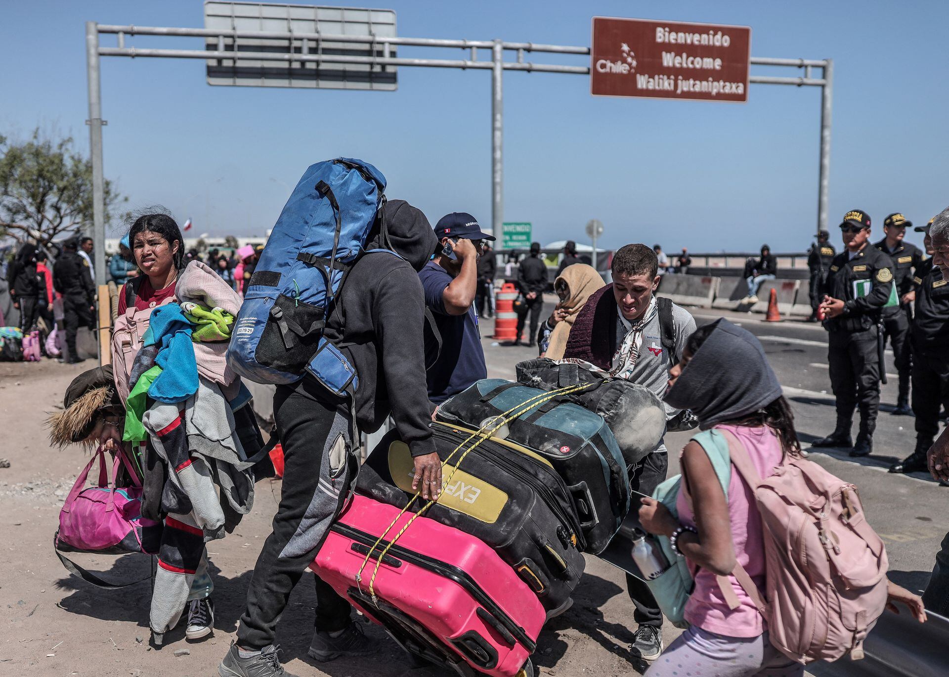 Migrantes de diferentes nacionalidades son escoltados por policías peruanos a una oficina de migración en Tacna, en la frontera entre Perú y Chile, el 28 de abril de 2023. - Chile confirmó que el 7 de mayo partirá un primer vuelo de repatriación para cientos de migrantes venezolanos varados en el fronteriza con Perú que buscan regresar a su país de origen desde hace semanas, dijo el 4 de mayo el canciller chileno, Alberto van Klaveren.