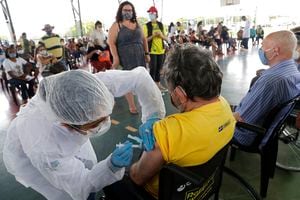 Una trabajadora de salud vacuna a un hombre en un centro de inoculación el lunes 22 de marzo de 2021 en el vecindario Ceilandia, en las afueras de Brasilia, Brasil. (AP Foto/Eraldo Peres)