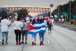 La gente sostiene una bandera cubana mientras bloquea una carretera durante una protesta contra el gobierno cubano, en Tampa, Florida, Estados Unidos