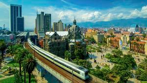 The elevated Medellin Metro is in motion as it rushes out of the Parque Berrio Station in front of the Palace of Culture in Plaza Botero in Medellin, Colombia. The City of Eternal Spring is located in the Aburra Valley, a central region of the Andes Mountains in South America.