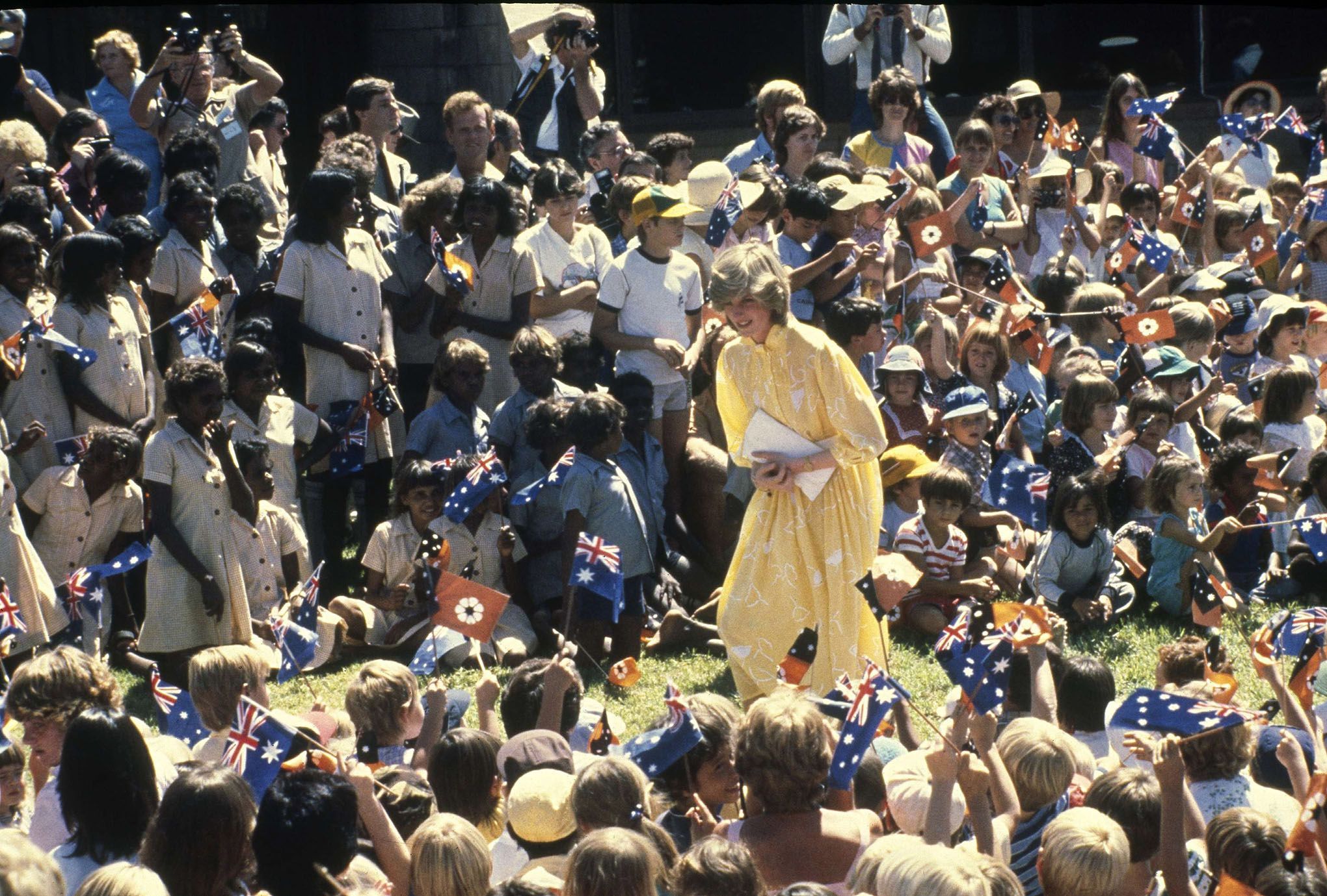 En esta fotografía de archivo del 21 de marzo de 1983, se muestra a Diana, princesa de Gales, en medio de un gran grupo de escolares durante su visita a Alice Springs, Australia. Diana sigue siendo considerada un ícono de la moda y sus vestidos se exponen regularmente en el Reino Unido, aprovechando el interés reavivado por la serie de Netflix The Crown.  Foto: AP / Dave Caulkin.