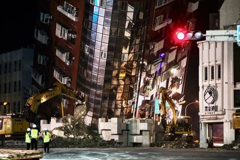 El personal de emergencia se encuentra frente a un edificio parcialmente derrumbado que se inclina sobre una calle en Hualien el 3 de abril de 2024, después de que un gran terremoto azotara el este de Taiwán (Foto de Sam Yeh / AFP)
