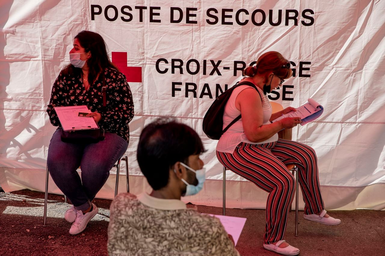 Mona Mohammad (izq) espera recibir su segunda dosis de la vacuna de Pfizer contra el COVID-19 en una instalación temporal de la Cruz Roja en Le Bourget, al norte de París, el 13 de agosto del 2021. (AP Photo/Adrienne Surprenant)