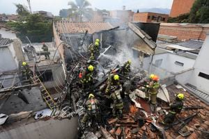 Firefighters work at the crash site of a small plane that fell on top of homes in a residential area of Medellin, Colombia, Monday, Nov. 21, 2022. The plane crashed shortly after taking off from Medellin's Olaya Herrera airport killing at least eight people including two members of the crew and his six passengers, according to city Mayor Medellin Daniel Quintero. (AP Photo/Jaime Saldarriaga)