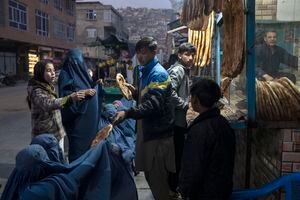 Un hombre distribuye pan a mujeres afganas que llevan burka fuera de una panadería en Kabul, Afganistán, el jueves 2 de diciembre de 2021. Según cifras de la ONU de principios de noviembre, casi 24 millones de personas en Afganistán, alrededor del 60% de la población, sufren del hambre aguda, incluidos 8,7 millones que viven cerca de la hambruna. Un número cada vez mayor de niños desnutridos ha llenado las salas de los hospitales. Foto AP / Petros Giannakouris