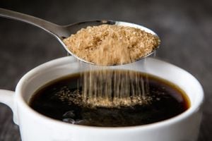 Azúcar moreno se vierte en la taza de café, primer plano