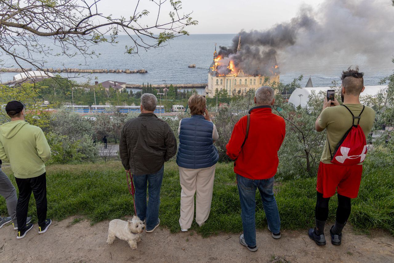 La gente mira hacia un edificio en llamas y dañado como consecuencia de un ataque con misiles en Odesa, el 29 de abril de 2024, en medio de la invasión rusa de Ucrania.