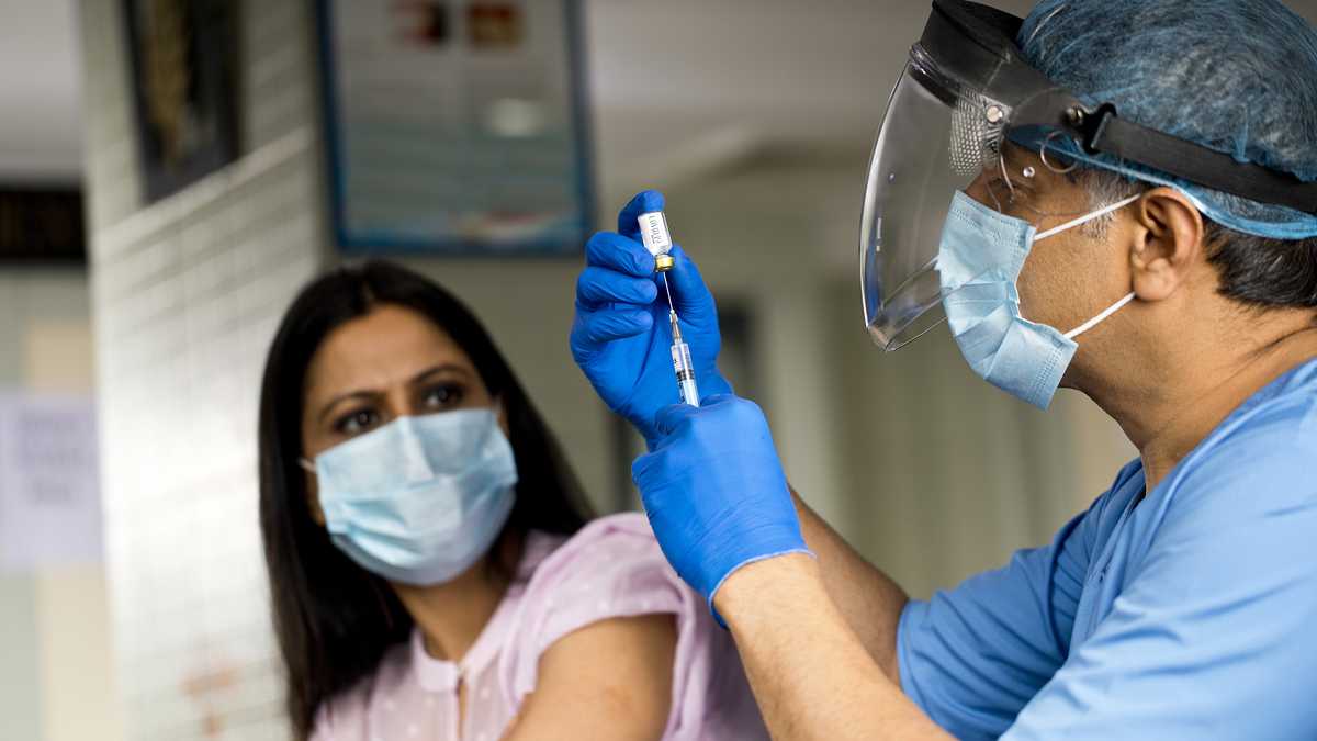 Doctor preparando la vacuna Covid-19 para paciente femenina