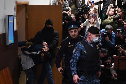 Un hombre sospechoso de participar en el ataque a una sala de conciertos en el que murieron 137 personas es escoltado por agentes del orden rusos antes de su audiencia de detención preventiva en en el Tribunal de Distrito de Basmanny en Moscú el 24 de marzo de 2024. (Foto de Olga MALTSEVA / AFP)