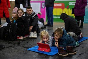 Los niños pasa el tiempo en los dispositivos electronicos en la estación de metro durante los ataques masivos con misiles rusos en Kyiv, Ucrania, el 14 de enero de 2023.