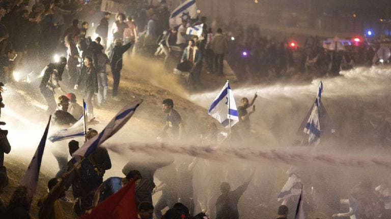 Policías israelíes emplean un cañón de agua para dispersar a los manifestantes que cortan una autopista durante una protesta contra los planes del primer ministro, Benjamin Netanyahu,