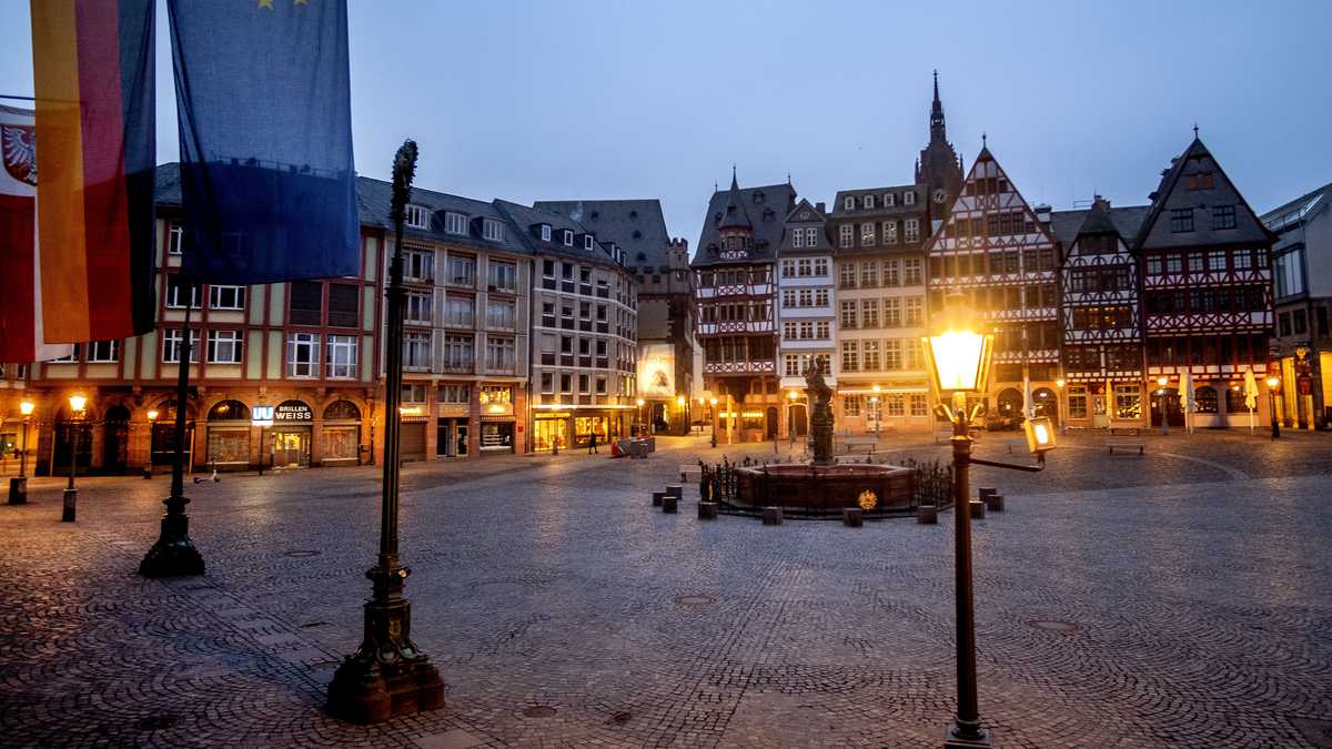 La plaza Roemerberg está vacía en Frankfurt, Alemania, la madrugada del martes 9 de marzo de 2021. Una bandera alemana y una europea están fijadas en el ayuntamiento de la izquierda. (Foto AP / Michael Probst)