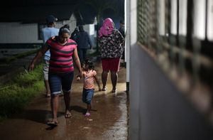 Una mujer y su hija caminan en un refugio temporal antes de la llegada de la tormenta tropical Bonnie en Bluefields, Nicaragua, el 1 de julio de 2022. (Photo by OSWALDO RIVAS / AFP)