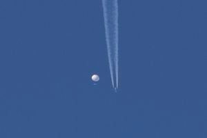 En esta foto proporcionada por Brian Branch, un gran globo se desplaza por encima de la zona de Kingstown, Carolina del Norte, mientras por debajo se observa un avión y la estela que deja a su paso