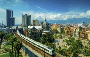 El Metro elevado de Medellín está en movimiento mientras sale de la estación Parque Berrio frente al Palacio de la Cultura en la Plaza Botero en Medellín, Colombia. La Ciudad de la Eterna Primavera está ubicada en el Valle de Aburra, una región central de la Cordillera de los Andes en América del Sur.