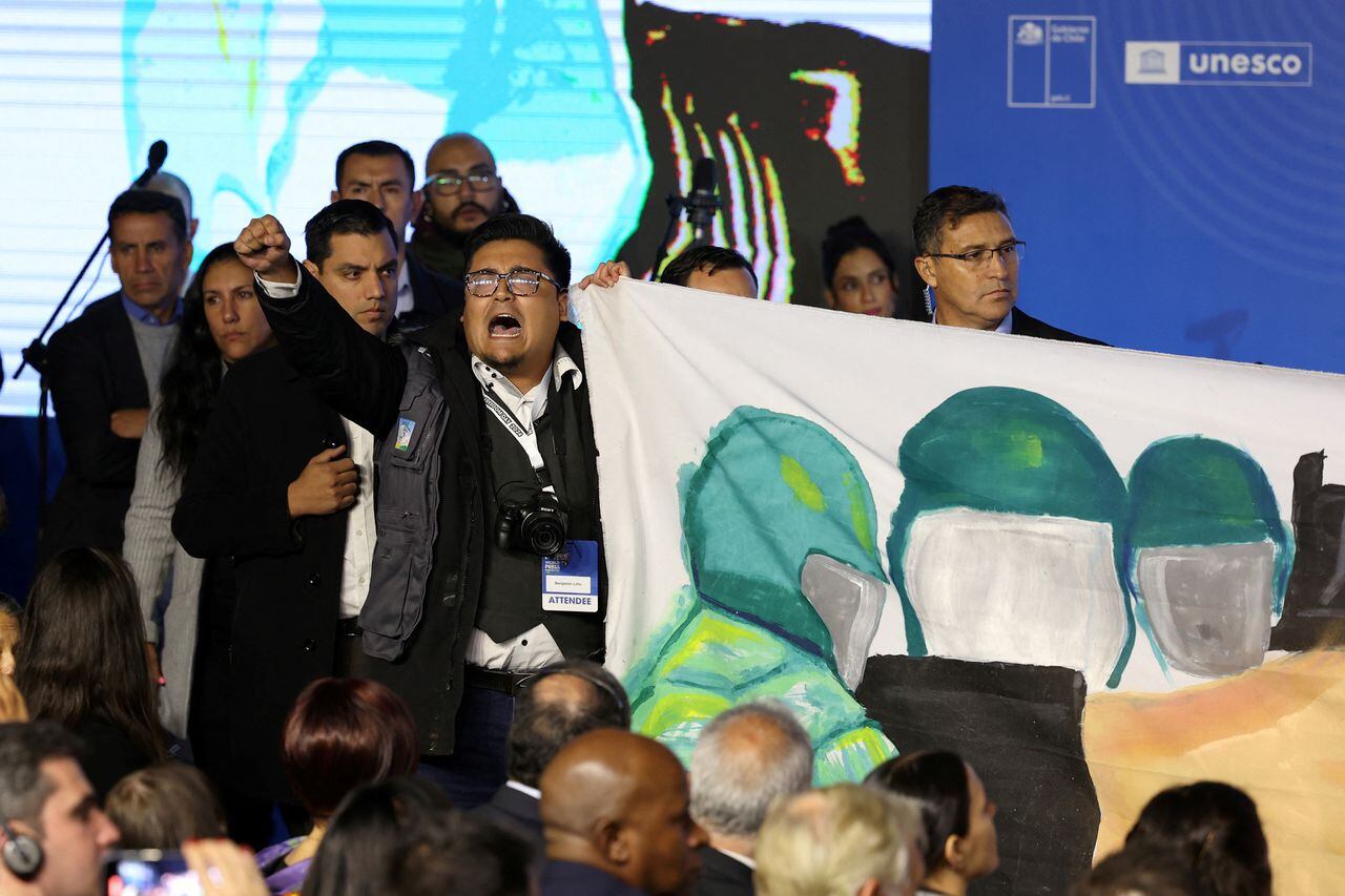 Un manifestante grita consignas mientras sostiene una pancarta sobre Francisca Sandoval, una periodista que fue asesinada a tiros durante una manifestación del Primero de Mayo de 2022, mientras el presidente de Chile, Gabriel Boric