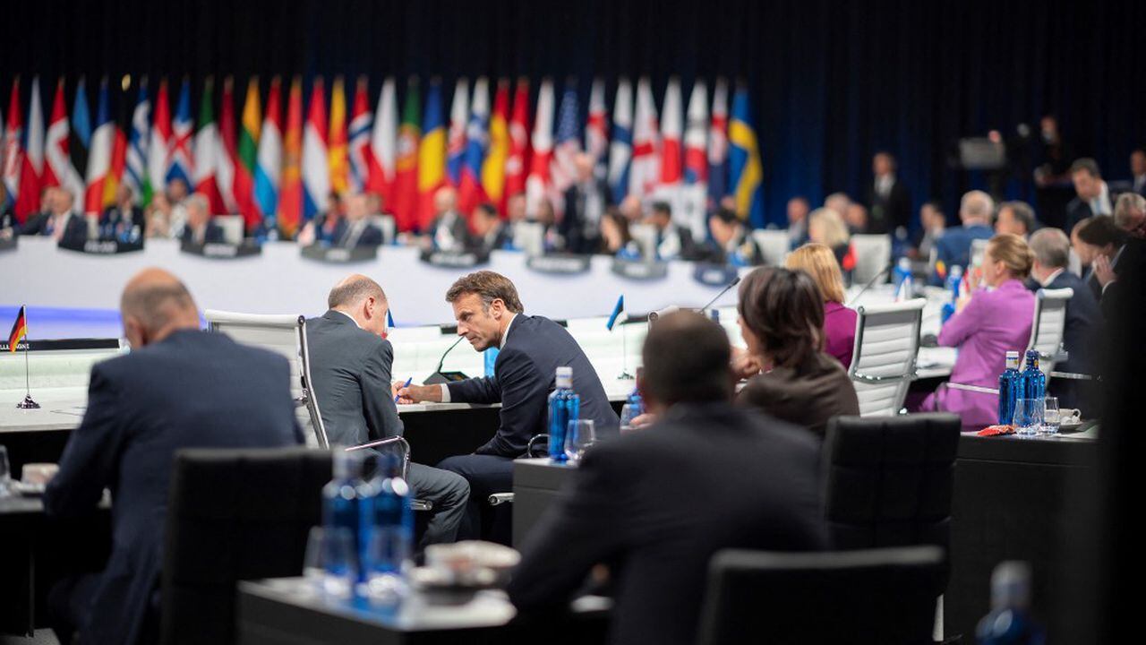 El presidente francés, Emmanuel Macron, habla con el canciller de Alemania, Olaf Scholz, al comienzo de la segunda sesión plenaria de la cumbre de la OTAN en el centro de congresos de Ifema en Madrid, el 29 de junio de 2022. (Foto de Eliot BLONDET / POOL / AFP)
