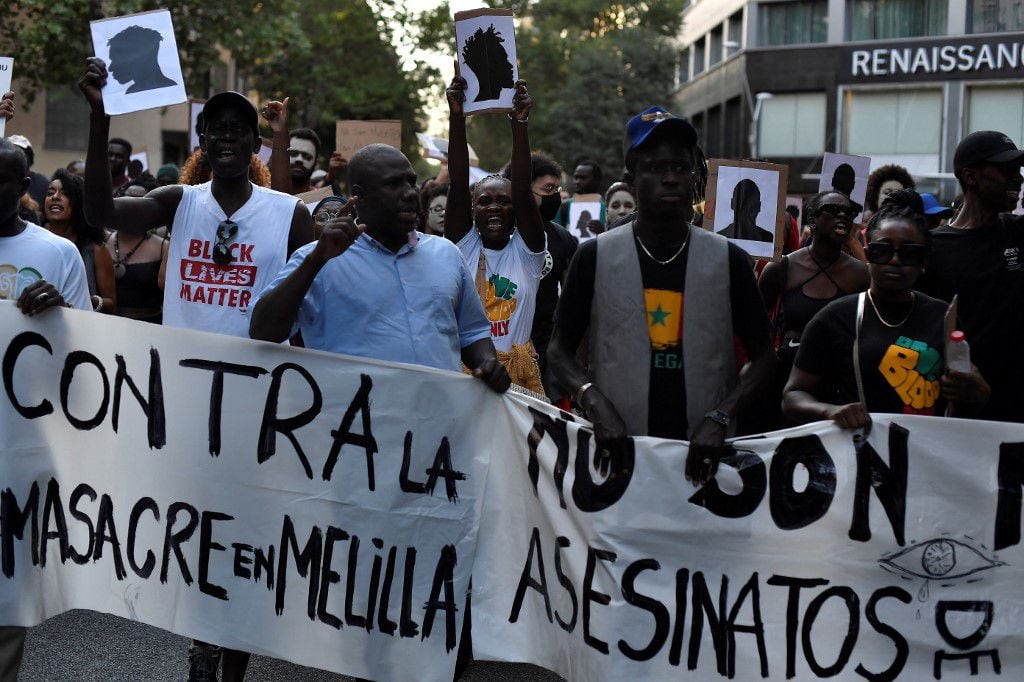 Manifestantes sostienen una pancarta que dice "Contra la masacre de Melilla" mientras participan en una manifestación antirracista "contra las muertes en las fronteras" en Barcelona el 1 de julio de 2022. - En la madrugada del 24 de junio, alrededor de 2.000 inmigrantes, en su mayoría del África subsahariana, trató de romper la valla de Marruecos a Melilla, uno de los dos pequeños enclaves de España en el norte de África. Las autoridades marroquíes dijeron que algunas de las víctimas se habían caído mientras intentaban trepar por la cerca, lo que dio un saldo inicial de 18 muertos, pero luego aumentó a 23 después de que otros cinco inmigrantes murieran a causa de sus heridas. (Foto de Pau BARRENA / AFP)