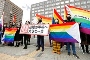 Abogados de los demandantes y partidarios posan con banderas arco iris, símbolo de la comunidad LGBTQ, y un cartel con el lema "Fallo inconstitucional" en el exterior del tribunal de distrito de Sapporo tras un juicio, en Sapporo, en el norte de Japón, el 17 de marzo de 2021. (Yohei Fukai/Kyodo News via AP)