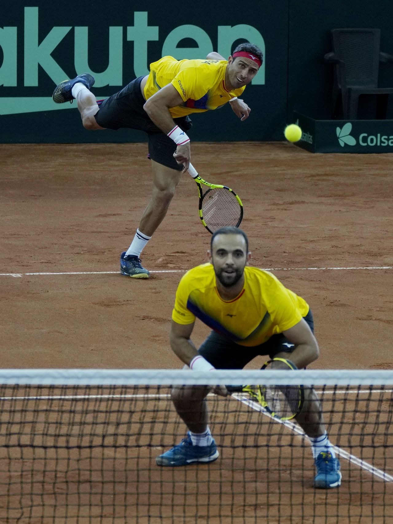 Colombia's Robert Farah, top, serves as teammate Juan Cabal, bottom watches during their Davis Cup qualification doubles match against Neal Skupski and Dan Evans of Britain, in Cota, Colombia, Saturday, Feb. 4, 2023. (AP Photo/Fernando Vergara)