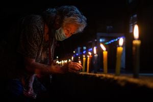 7/12/20. Carmen Alicia García , de 82 años, ubica una vela en la entrada del Ancianato San Miguel durante el Día de las Velitas.