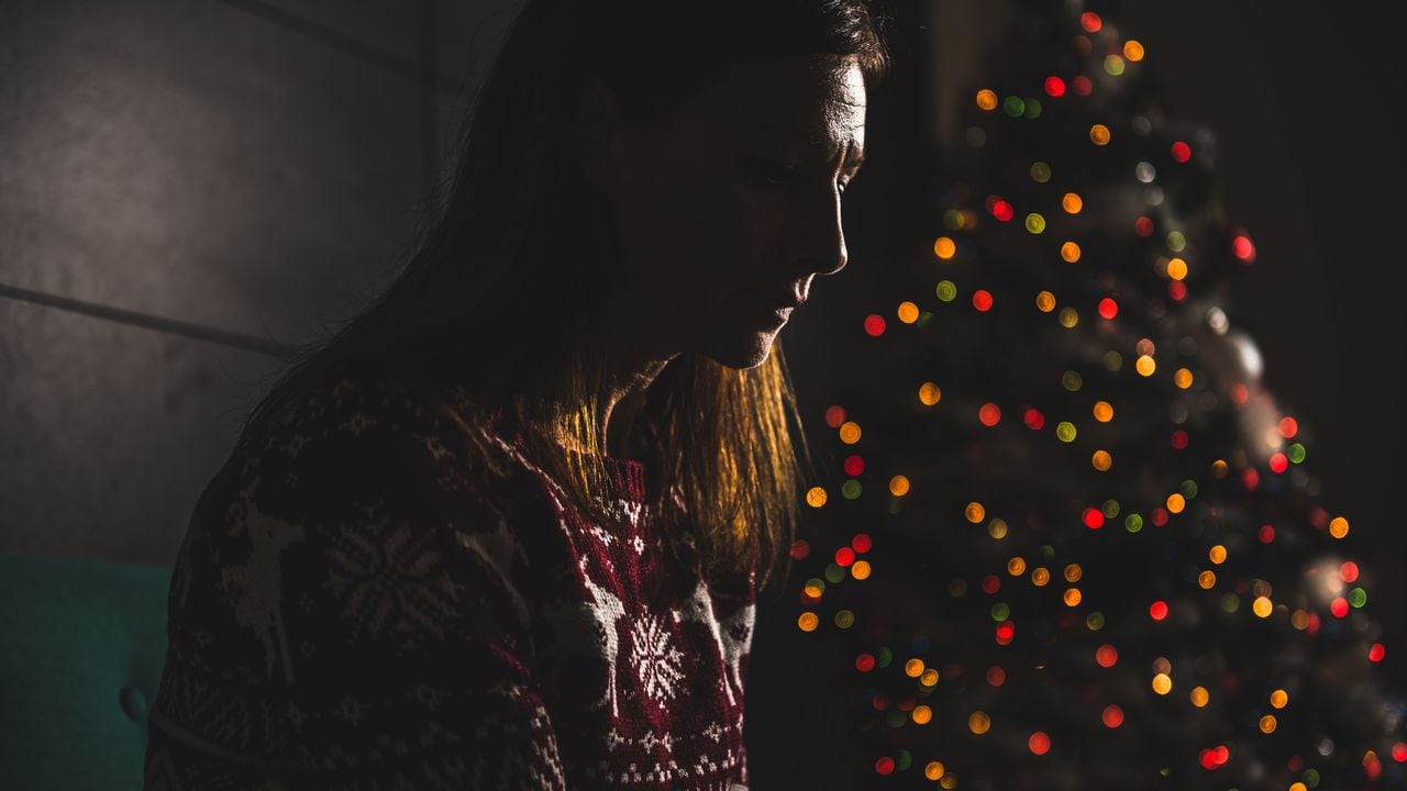 Foto de referencia de una mujer y, de fondo, un árbol de Navidad
