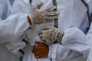 Los miembros de la familia se abrazan mientras usan equipo de protección personal mientras lloran a un familiar varón, que murió a causa de la enfermedad del coronavirus, durante su ceremonia de cremación en Nueva Delhi, India, el 21 de abril de 2021. Foto REUTERS/Adnan Abidi