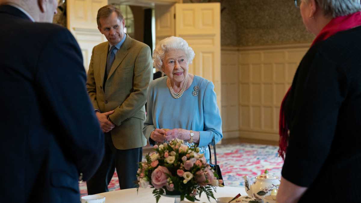 estida con un traje azul claro y adornada con un collar de perlas y un bastón en la mano, la reina cortó un pastel preparado para la ocasión (Photo by Joe Giddens / POOL / AFP)
