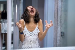 Mujer enojada gritando al espejo y llorando
